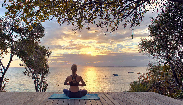 Woman on deck doing yoga overlooking the ocean in Mozambique