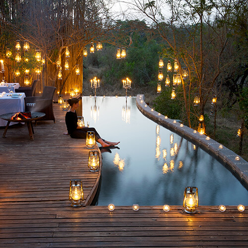Woman sitting by candlelit pool at Londolozi pioneer camp