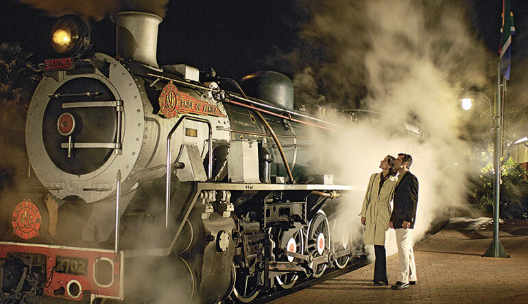 Couple looking at Rovos Rail steam train in station