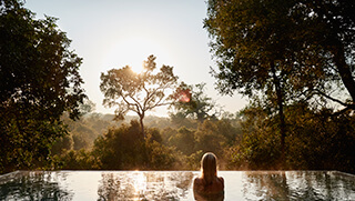 Woman in pool overlooking the African bush at Royal Malewane