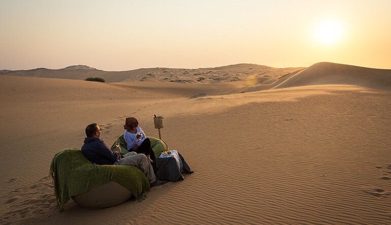 Couple enjoying sunset drinks in the desert in Namibia