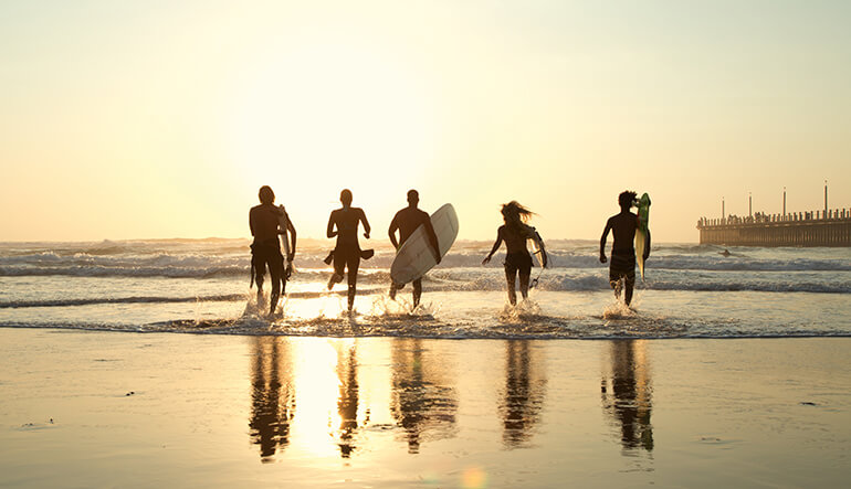 Silhouette of five surfers running into the beach in Durban KwaZulu-Natal
