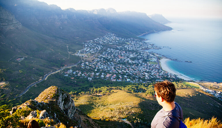 Man looking at Camps Bay from the top of Lions Head