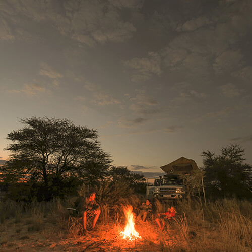 Father and sons around a fire during a self drive safari in Botswana