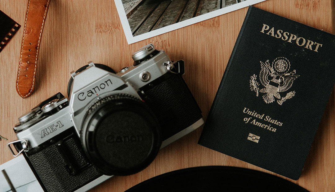 Canon camera and passport on wooden desk