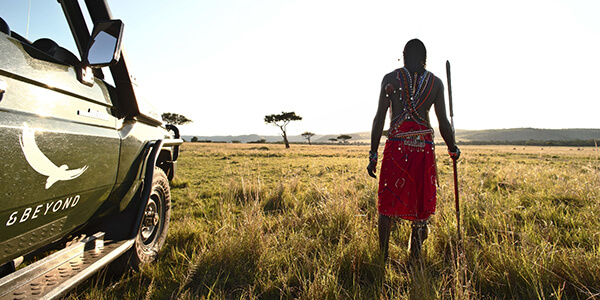 Maasai man next to safari vehicle at andBeyond Kichwa Tembo Camp in Kenya