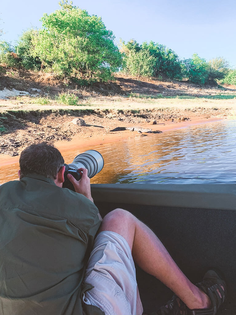 Man taking a photograph of a crocodile on the Chobe River in Botswana